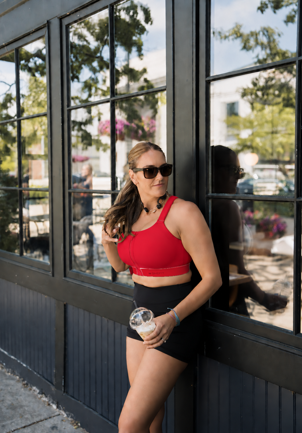 Woman in Scarlet Heat Emerge outside a café holding an iced drink
